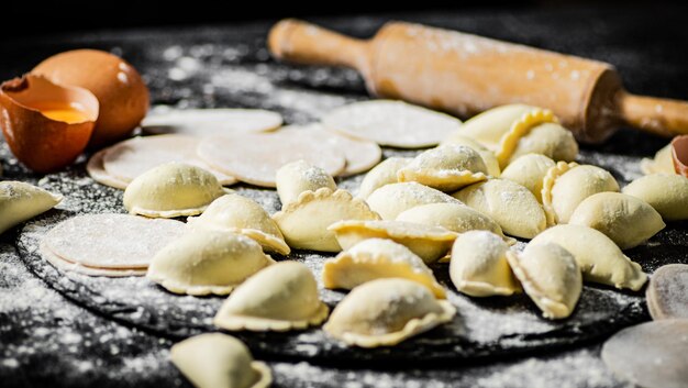 A table full of dumplings and flour with a rolling pin next to it