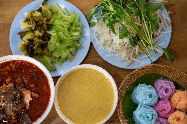 A table full of food including a variety of sauces and other dishes including thai food.