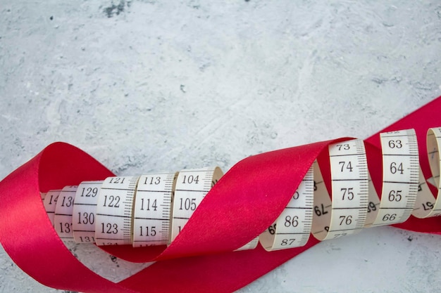 On the table is a measuring tape tied with a red satin ribbon The concept of needlework sewing