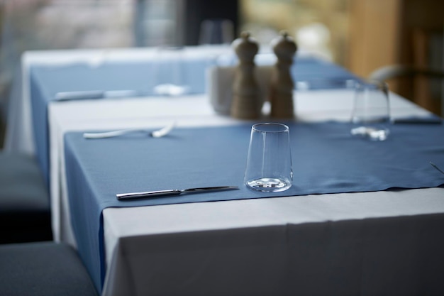 The table is set in a stylish and minimalistic way glasses on a
blue tablecloth