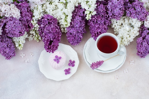 On the table is tea and marshmallows, and a bouquet of lilacs