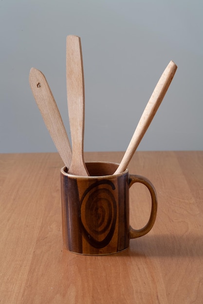 On the table is a wooden mug with wooden spoons.