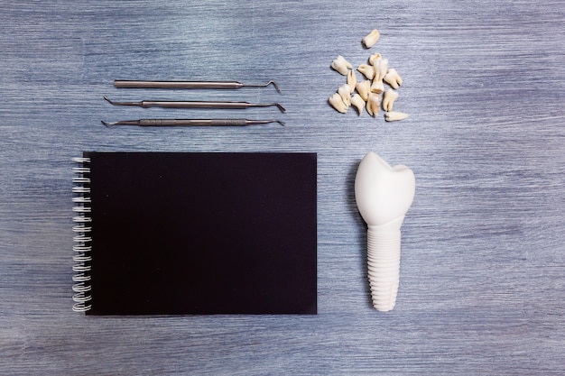 On the table lie the instruments of the dentist with black notepads and ragged teeth