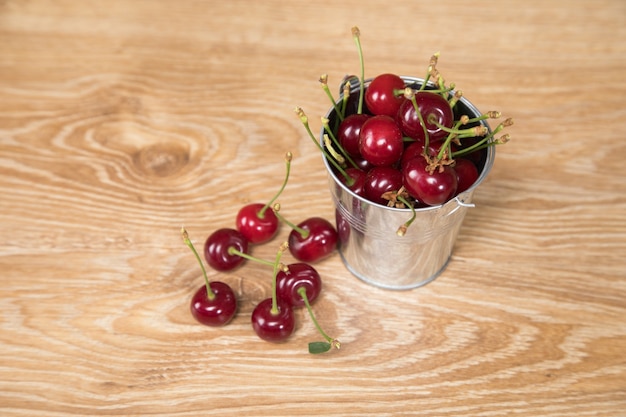 On the table red cherries in a small bucket