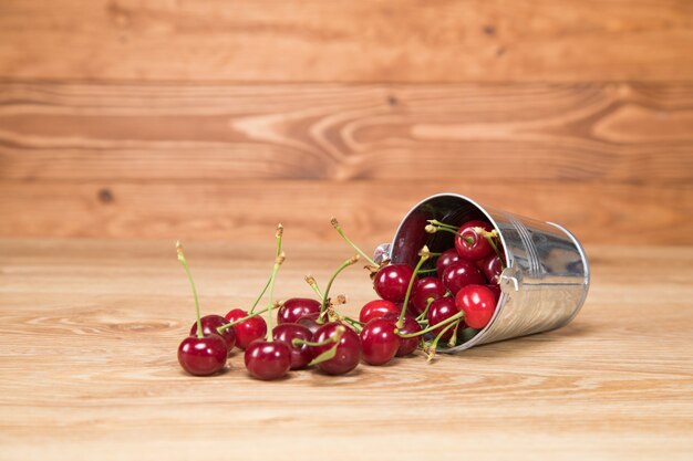 On the table red cherries in a small bucket