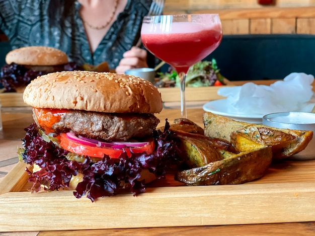 レストランのテーブルの上に子牛のカツレと赤玉ねぎのバジルとトマトのリングが付いたハンバーガー