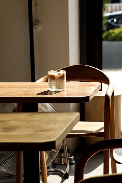 A table in a restaurant with a lamp on the table and a glass of coffee on the table.