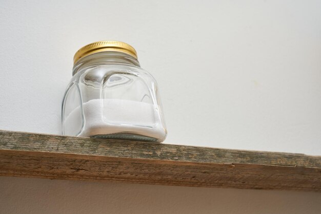 Table salt in a vintage jar on a wooden kitchen shelf.