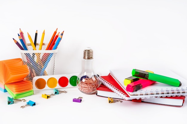 A table for a school with colored stationery paints an alarm clock on a white background