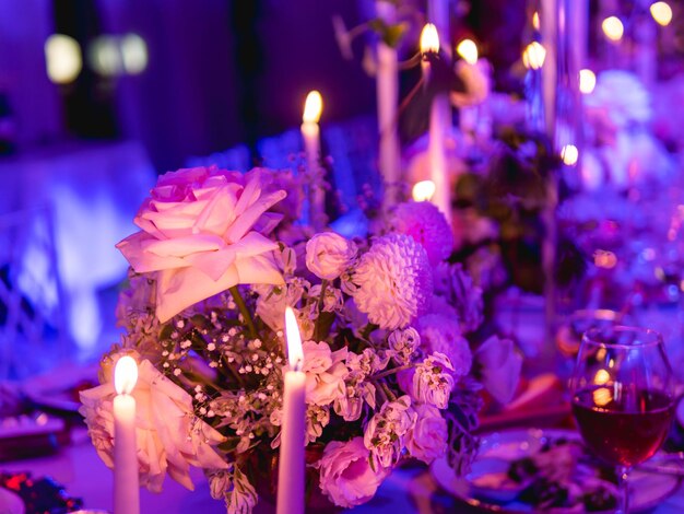 Table served for banquet with candles and floral compositions beautiful decorations in pink and purple electric light