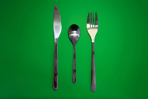 Table serving-knife,plate,fork on  green colour background.