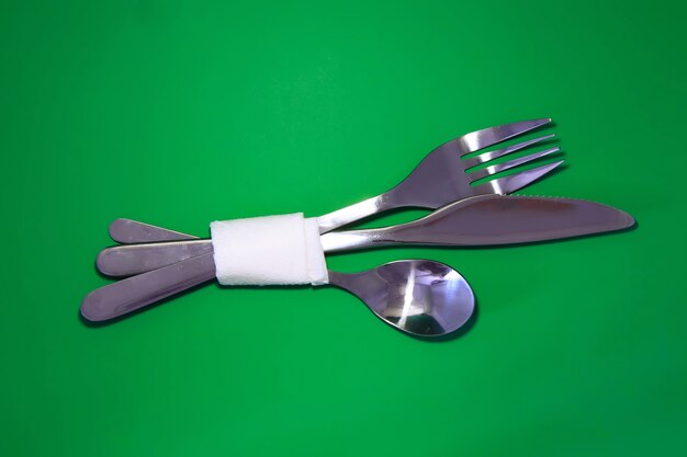 Photo table serving-knife,plate,fork and silk napkin  on  green colour background.