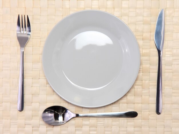 Table serving-knife,plate,fork on  various colour background.