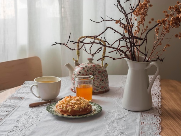 Table set for tea in a cosy living room Cup of green tea honey a sweet bun on a round table