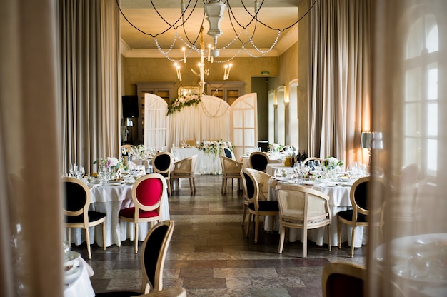 Table set at the wedding Banquet in the restaurant, classic style with white tablecloths and napkins, vases with flowers.