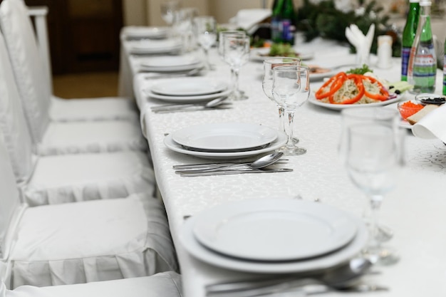 A table set for a wedding dinner with a plate of vegetables and a bottle of wine.