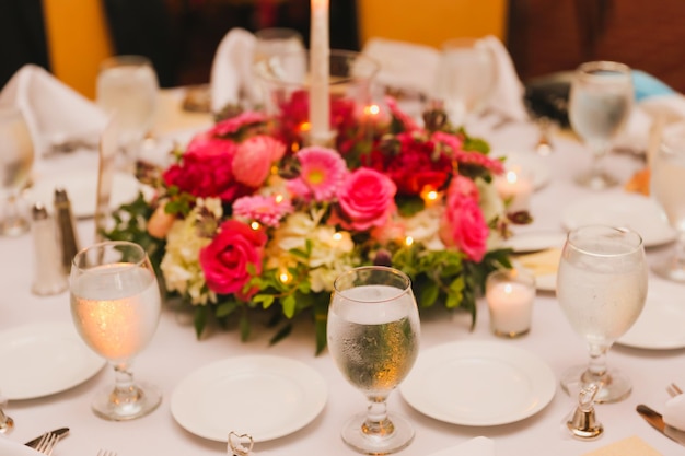 A table set for a wedding reception with a flower centerpiece