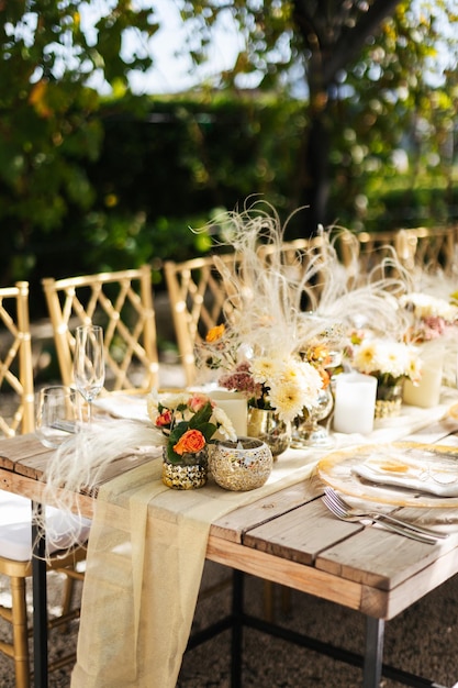 A table set for a wedding reception with a yellow tablecloth and white feathers.