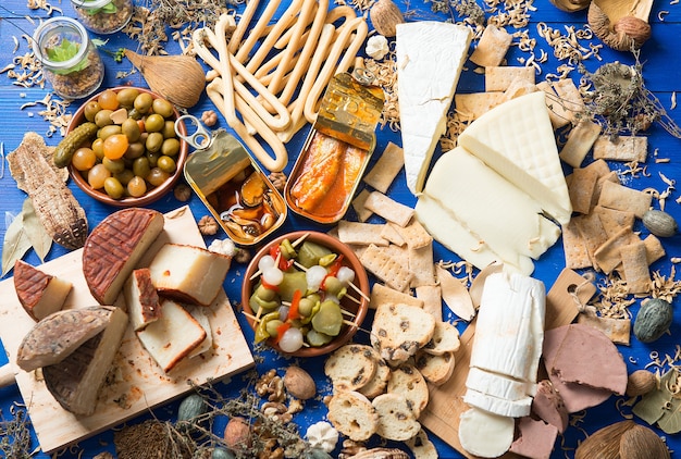 table set with an aperitif consisting of different foods cheeses and cans of pickles