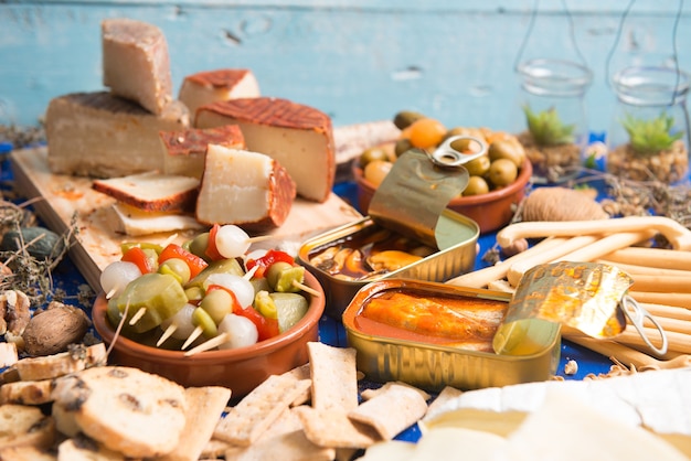 table set with an aperitif consisting of different foods cheeses and cans of pickles