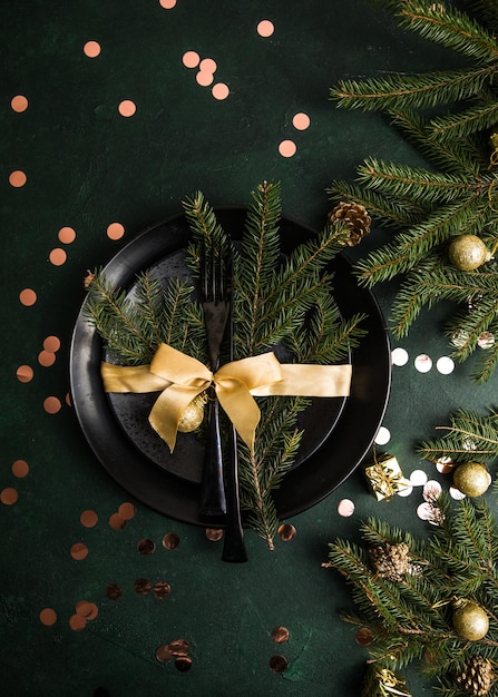 Impostazione della tabella per le feste di natale e capodanno sul tavolo. posto festoso per la cena di natale con piatto nero e decorazioni naturali. vista dall'alto. copia spazio.