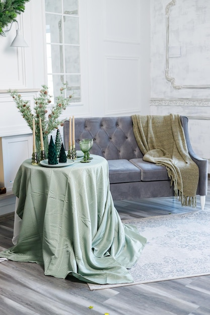 Table setting for Christmas or New Year's dinner with candles decorations tablecloth and napkins on the background of a Christmas tree in an apartment