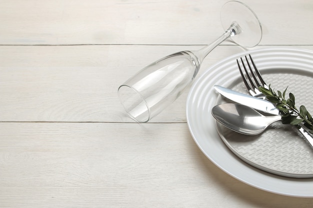 Regolazione della tavola. posate. forchetta, coltello, bicchiere, cucchiaio e piatto su un tavolo di legno bianco.