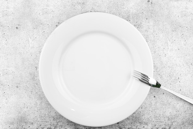 Photo table setting. empty plate, fork on a light concrete