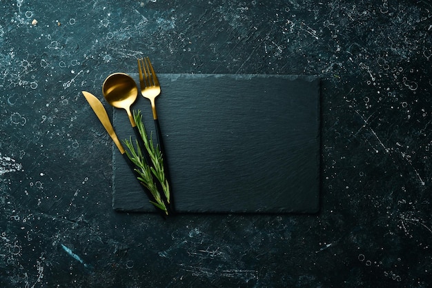 Table setting. Slate black stone plate with cutlery. Top view. Free copy space.