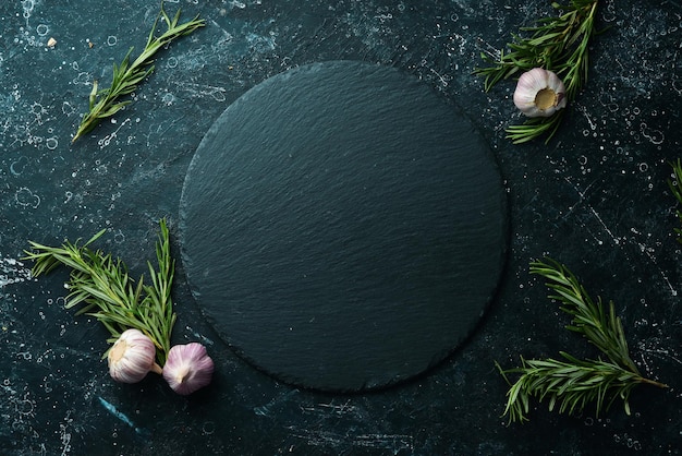 Table setting Slate black stone plate with rosemary and garlic Top view Free copy space