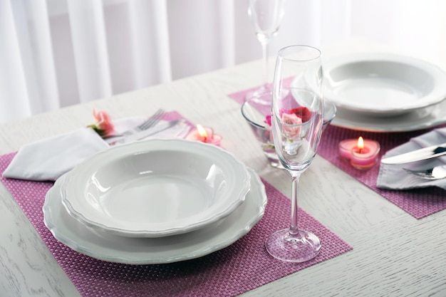 Table setting for two person with dishes and cutlery on pink napkin