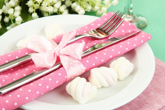 Table setting in white and pink tones on color wooden background