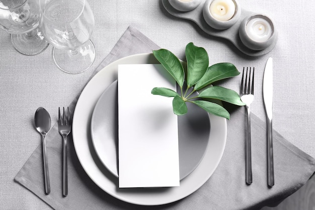 Table setting with green tropical leaves on grey napkin