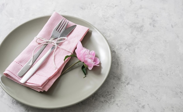 Table setting with light green ceramic plates and pink peonies on concrete table