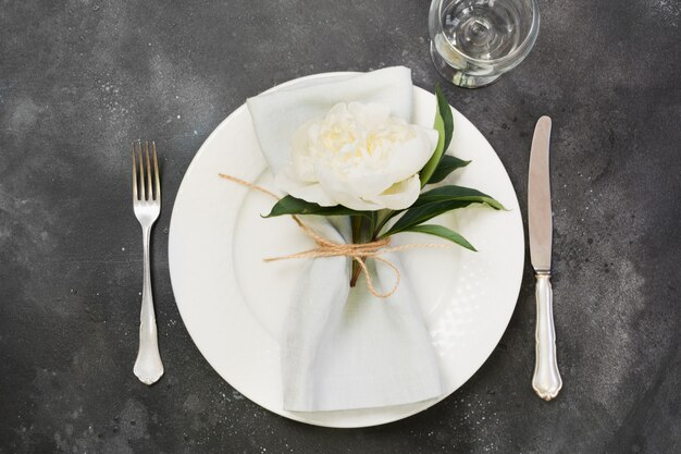 Table setting with white peony on black table