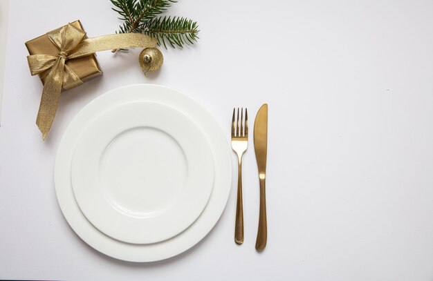 Настройка стола на Рождество Новый год Золотые приборы на белом наборе посуды на белом фоне