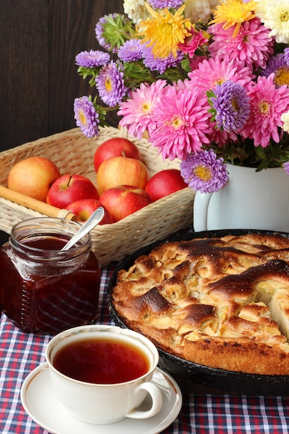 Table-still life with pie, red apples, jam, tea in the Cup and a bouquet of pink chrysanthemums 