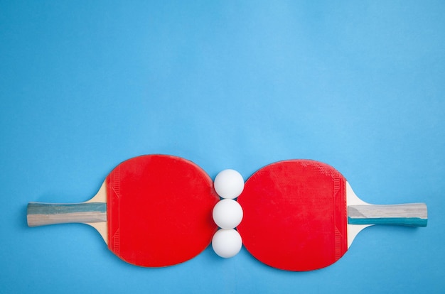 Photo table tennis rackets and a white plastic balls on a blue background