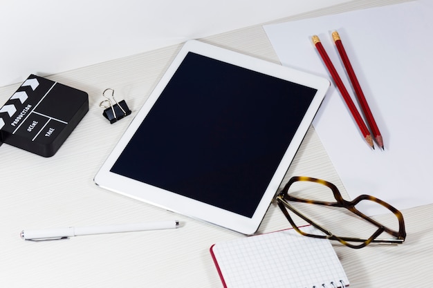 On the table there is a tablet, pencils, notebook, pen, glasses 