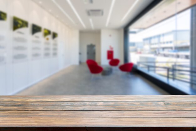 Table top in a big room blurred in the background with a big window and red sofas.