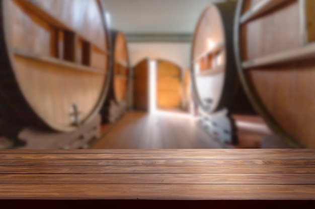 Photo table top in a blurred wine room with big wine barrels throughout the room.