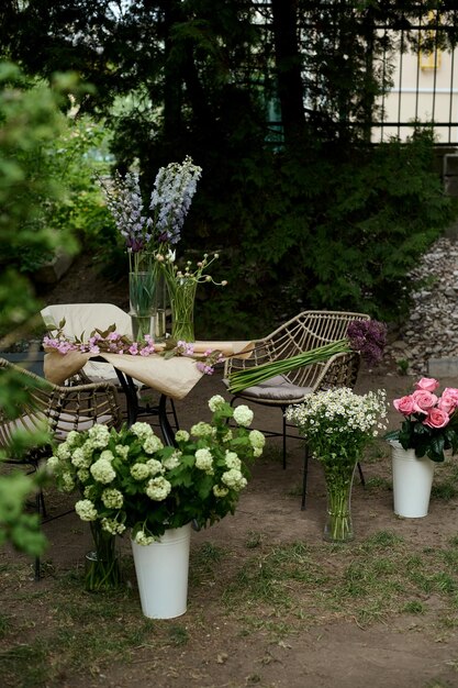 A table and two chairs in the garden with a vase of flowers on it and two more on the grass