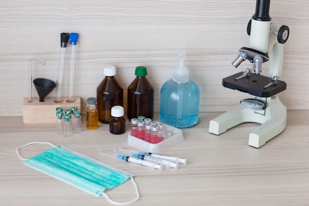 Photo on the table: vaccines in ampoules, syringes, protective mask