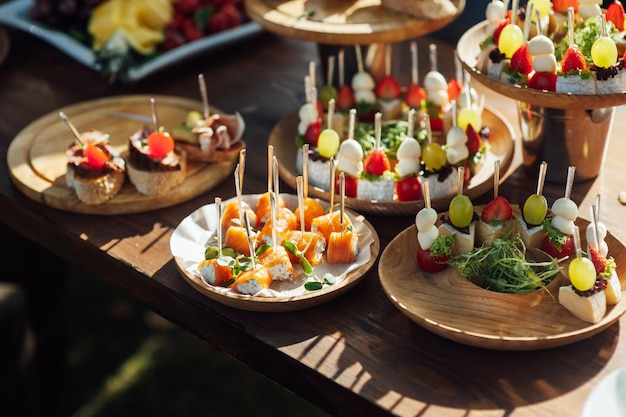 Un tavolo di vari snack, tramezzini, fragole e altri tipi di snack tavolo da banco per gli ospiti di una festa di matrimonio