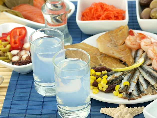 青い市松模様のテーブル クロスとエビ、エビ、水、その他の食品を含むグラスが置かれたテーブル。