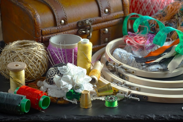 A table with a bunch of sewing supplies including a sewing machine, a sewing machine, and a box.