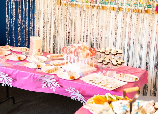 Table with cake and desserts at the little girl's birthday party.