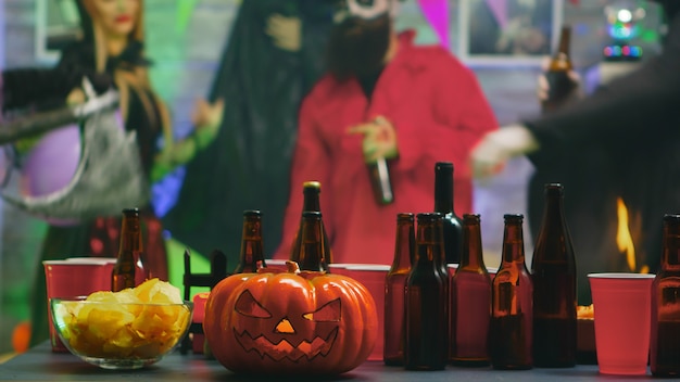 ダンスパーティーでハロウィーンを祝う人々のグループのためのチップスとビールのテーブル