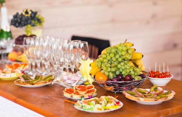 Table with cold snacks and tableware on standup party