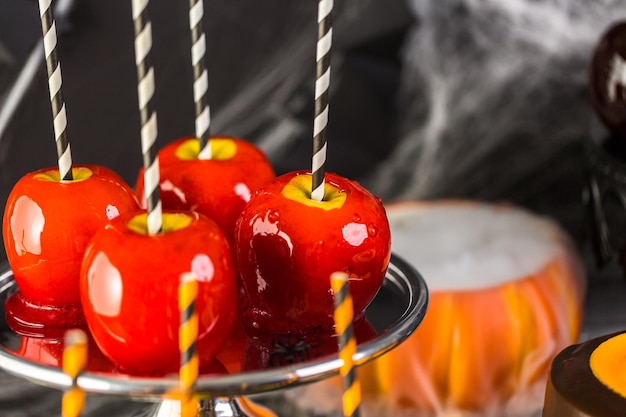 Table with colored candy apples and cake for Halloween party.